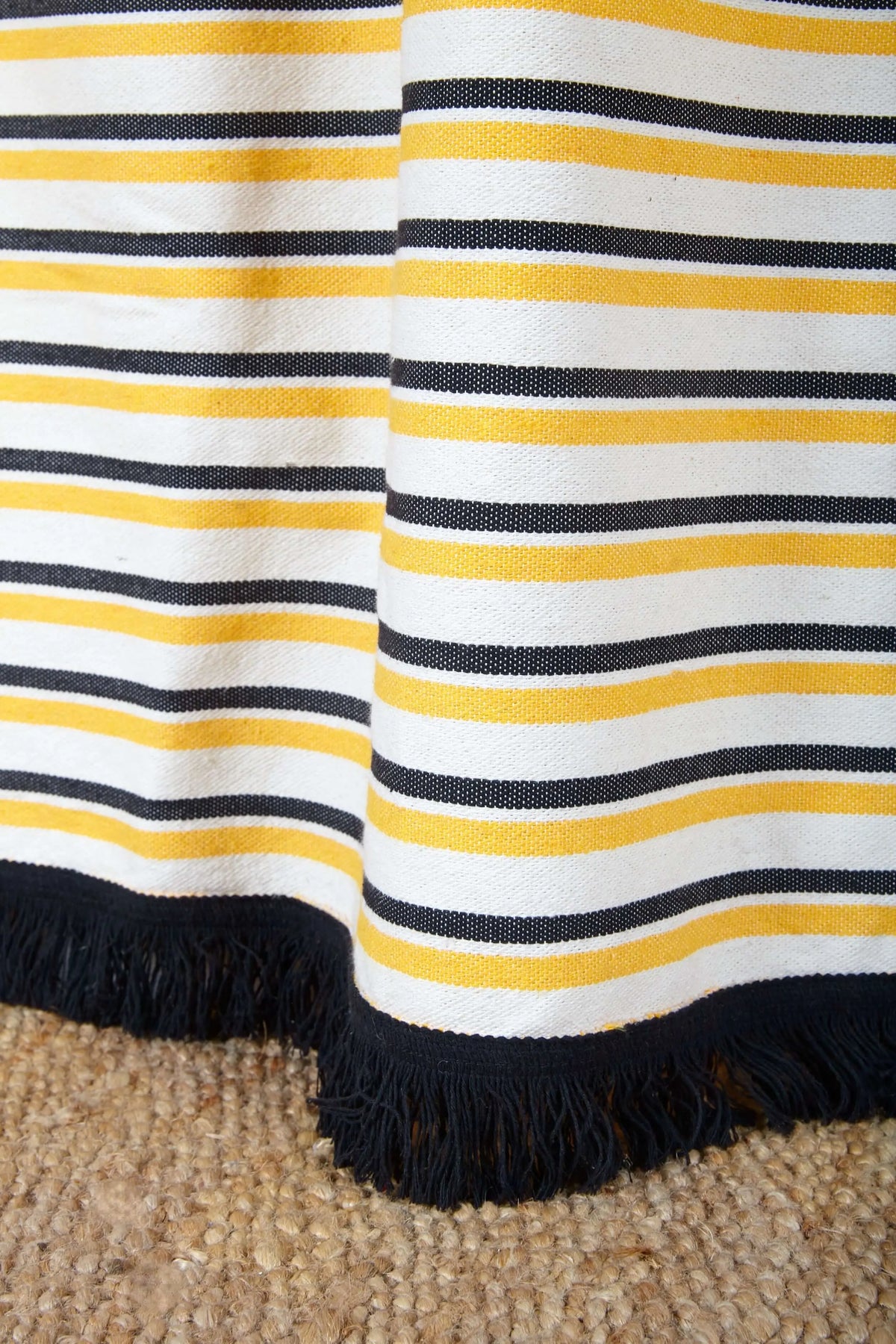 Textured canvas curtain featuring horizontal yellow, black, and white stripes with a decorative black fringe hem.