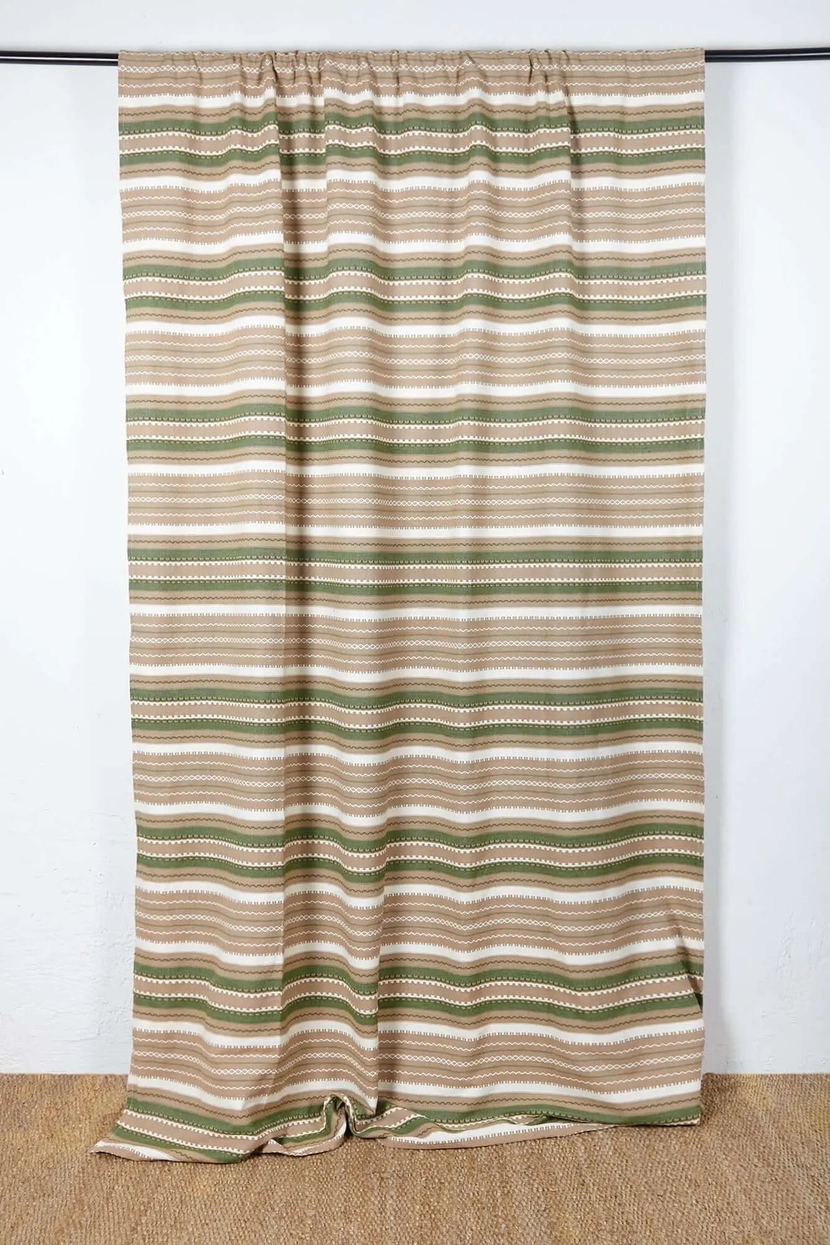 Handcrafted curtain with green, brown, and white horizontal striped patterns on a textured fabric.