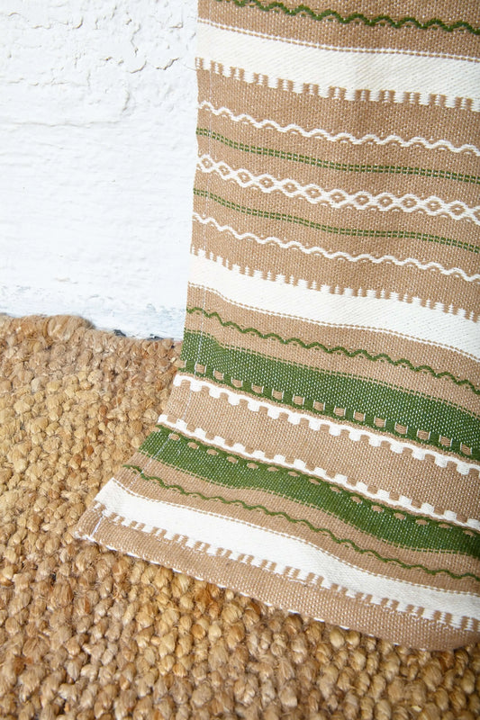 Artisanal curtain with a woven texture, featuring brown, cream, and green horizontal stripes and decorative patterns.