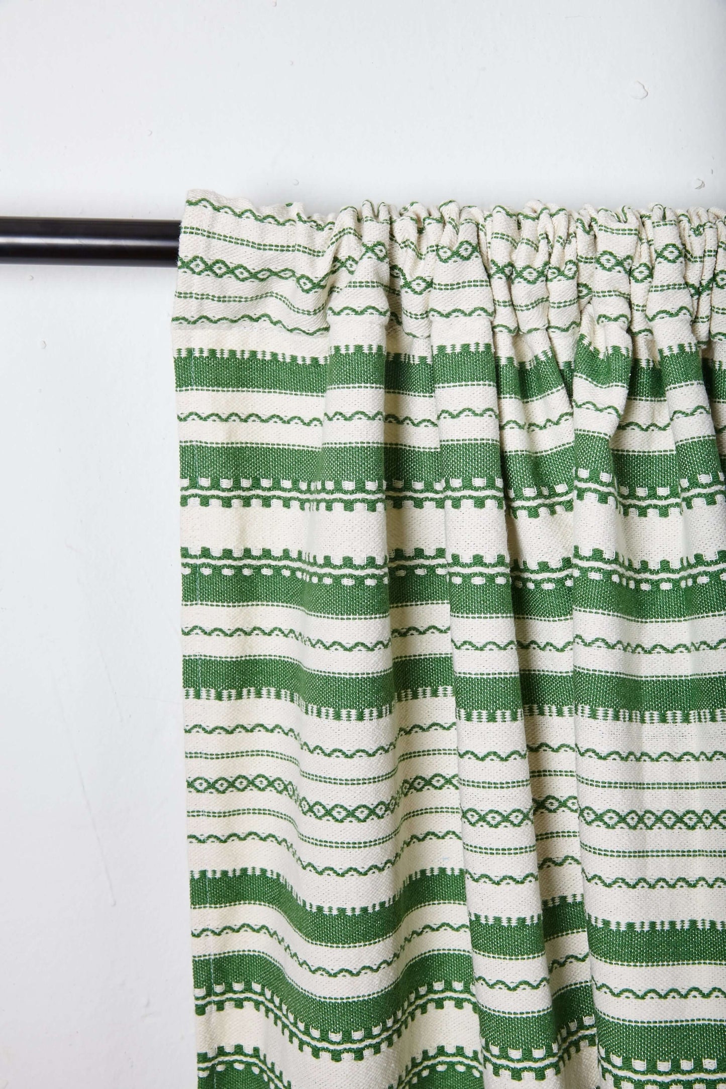 Cortina artesanal estilo alpujarra en blanco y verde con patrones geométricos tejidos sobre fondo de algodón.