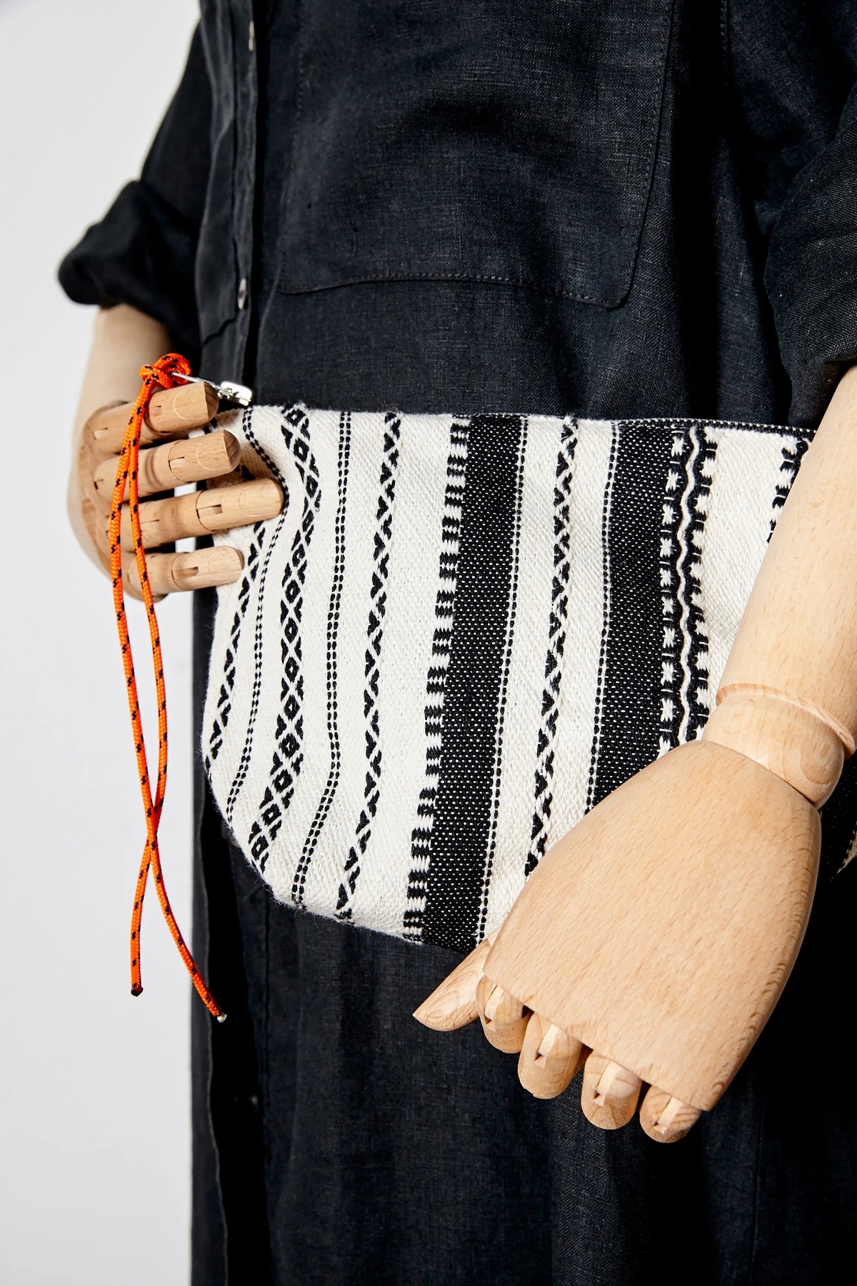 Neceser de tela con estampado de rayas blancas y negras, estilo artesanal alpujarra, con cordón naranja en la cremallera.