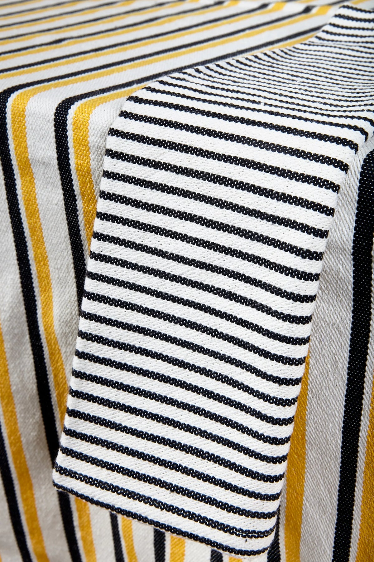 Mantel de loneta con estampado de rayas verticales en amarillo, negro y blanco, estilo moderno y resistente.
