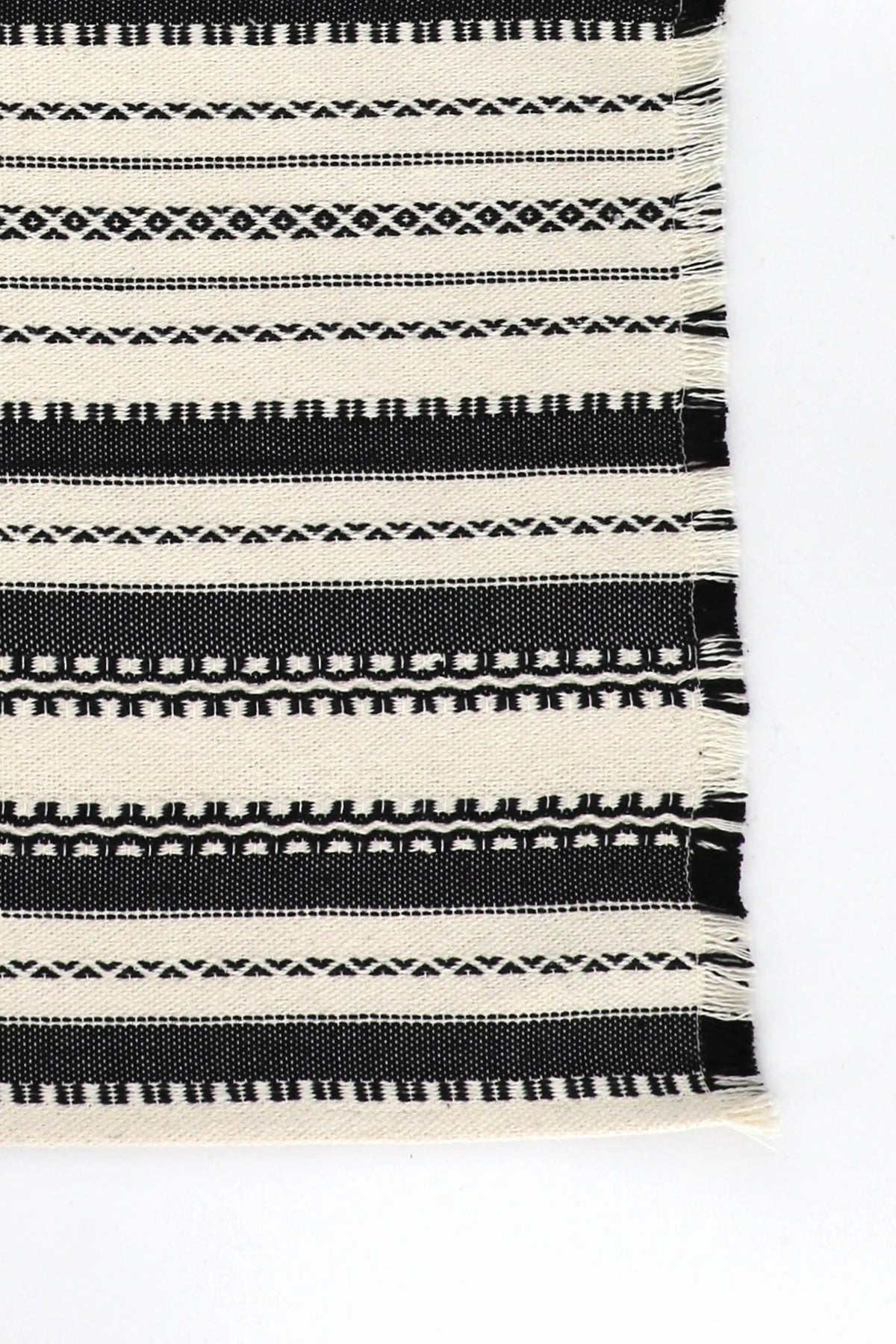 Black and white woven placemat with geometric patterns, horizontal stripes, and a frayed fringe edge.