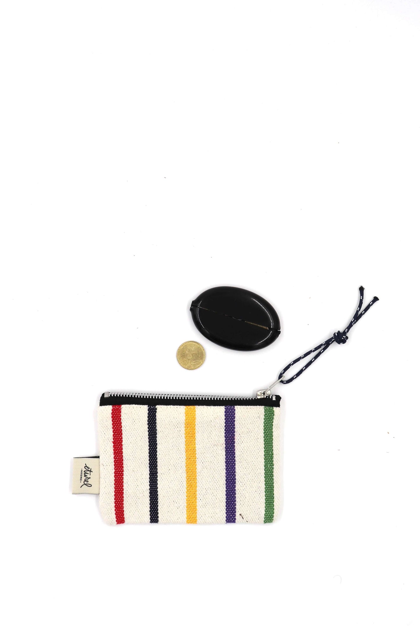 Monedero de tela tejido con rayas verticales de colores sobre fondo crema, cierre de cremallera y cordón decorativo.