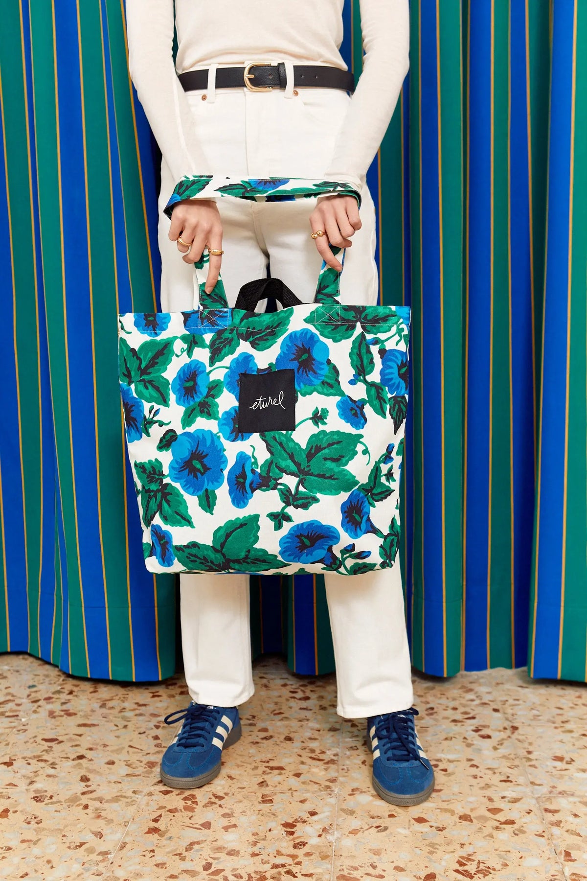Bolso tote de lona blanca con estampado de flores azules y hojas verdes, estilo casual y resistente.