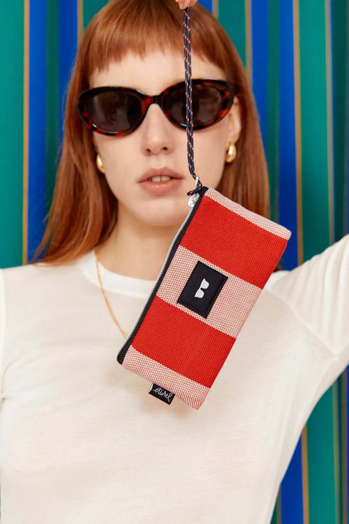 Funda para gafas de lona con rayas rojas y crema, estilo toldo, con cierre de cremallera y cordón para colgar.