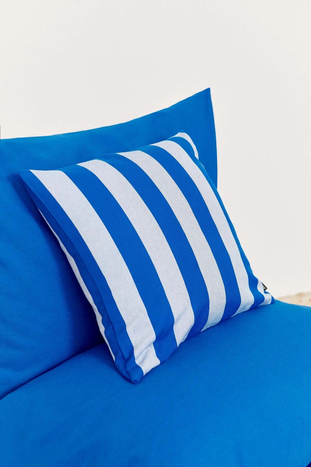 Funda de cojín de 50x50 cm en lona azul y blanca con diseño de rayas estilo náutico, ideal para exterior.