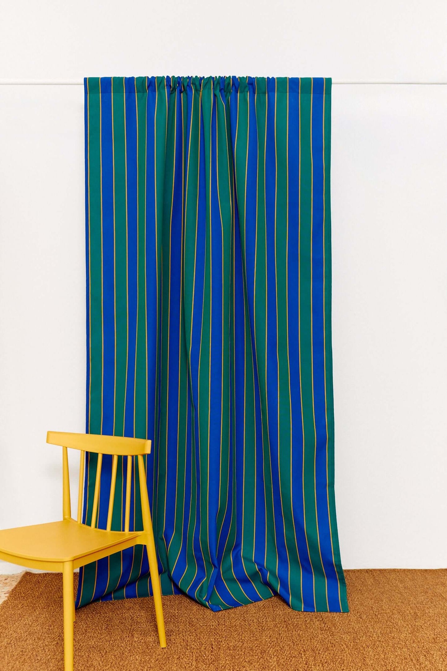 Cortina de lona con rayas verticales en azul, verde y amarillo, con caída recta y estilo decorativo moderno.