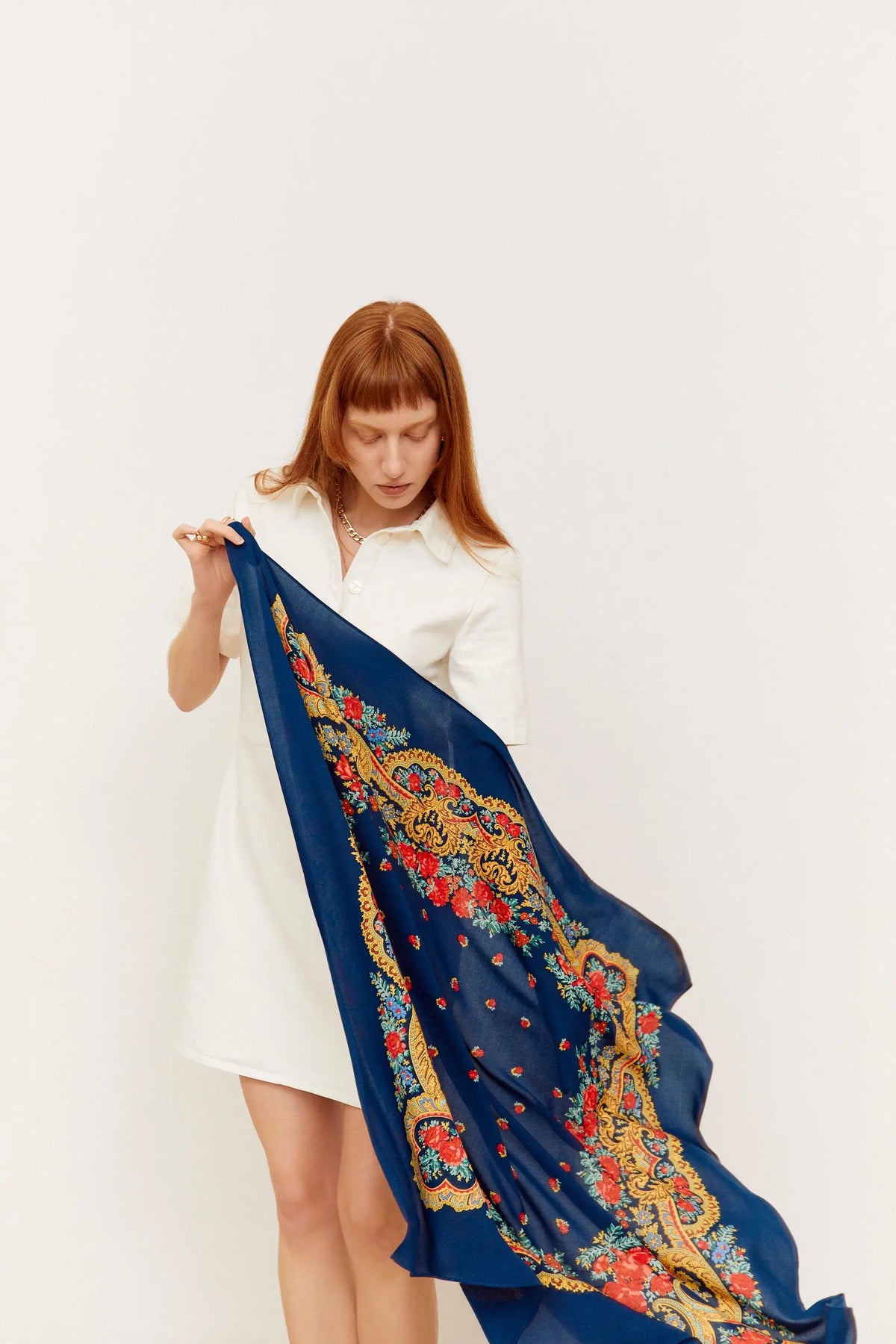 Pañuelo azul marino con estampado floral, motivos de cadenas doradas y detalles barrocos en tela ligera.
