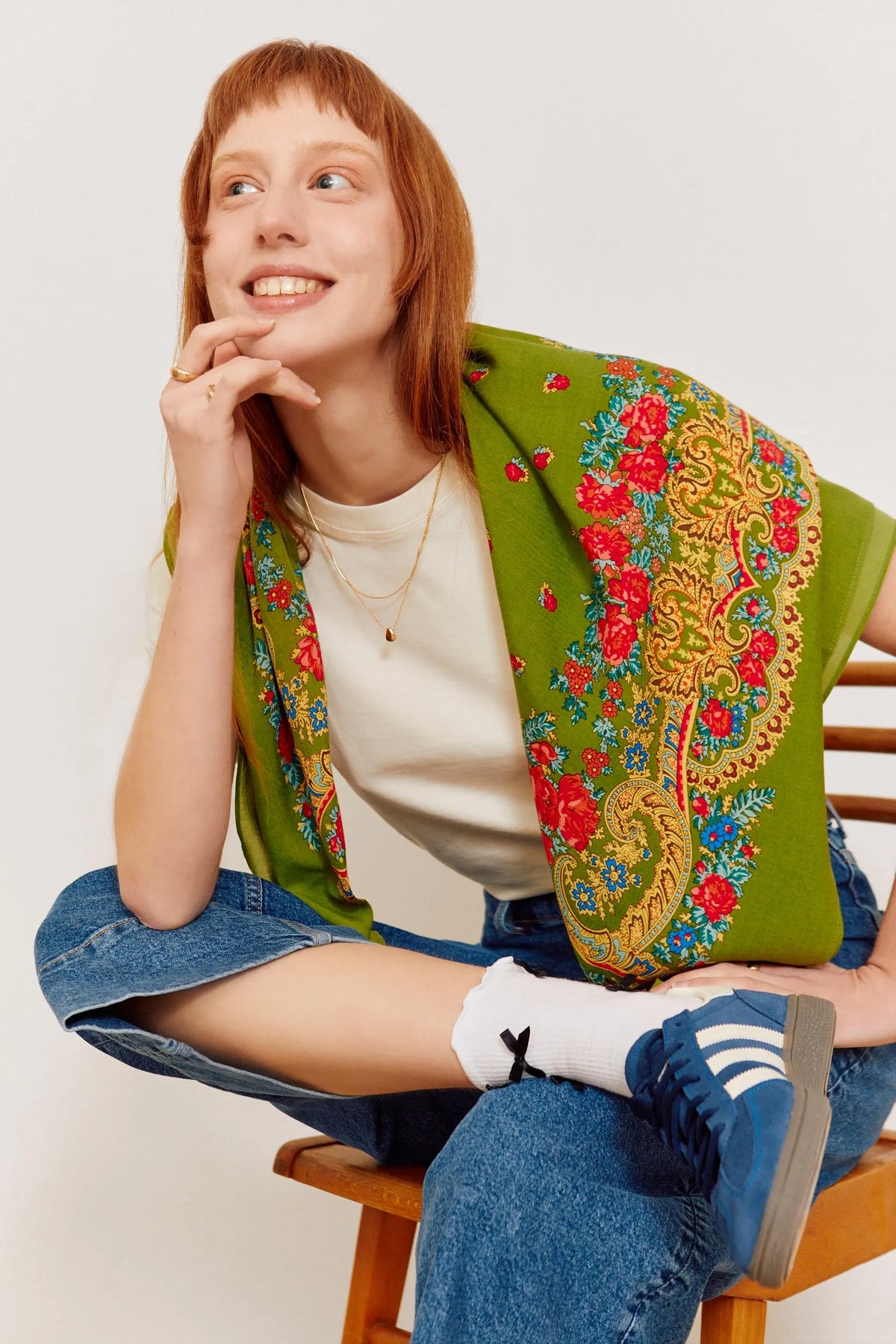 Mujer con pañuelo verde oliva estampado con flores rojas y motivos dorados tipo cadena, estilo tradicional portugués.