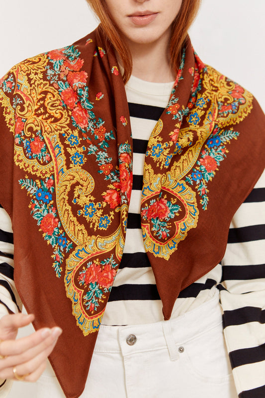 Pañuelo color moca con estampado floral y ornamentos dorados estilo tradicional, usado sobre camiseta de rayas.