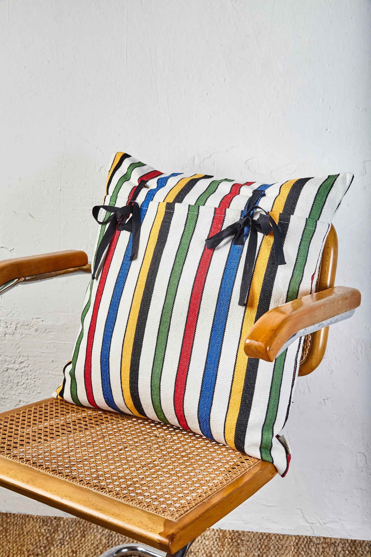 Cojín de rayas multicolores, algodón, con lazos negros, estilo moderno, ideal para decorar.