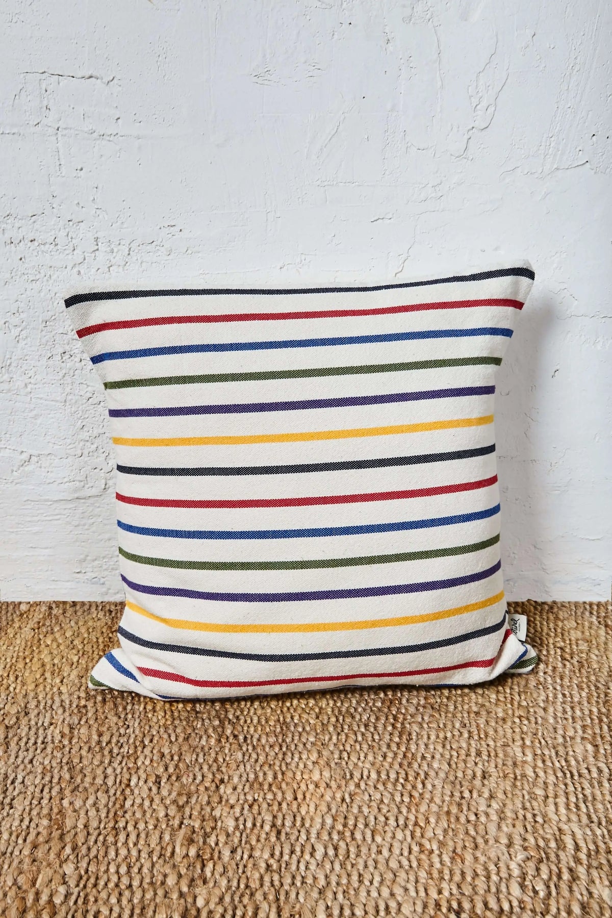 Funda de cojín de 50x50 cm con diseño de rayas horizontales multicolores sobre fondo de tejido natural.