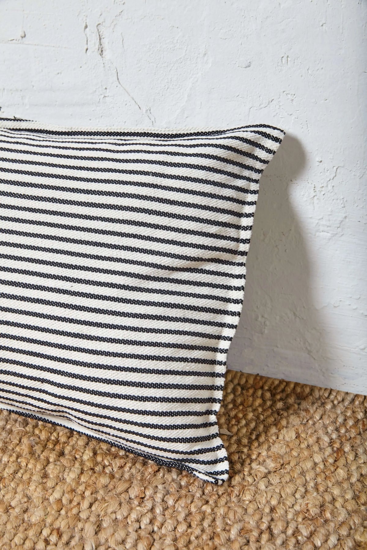 Funda de cojín rectangular de loneta con estampado de finas rayas horizontales en blanco y negro. Tamaño 30x50 cm.