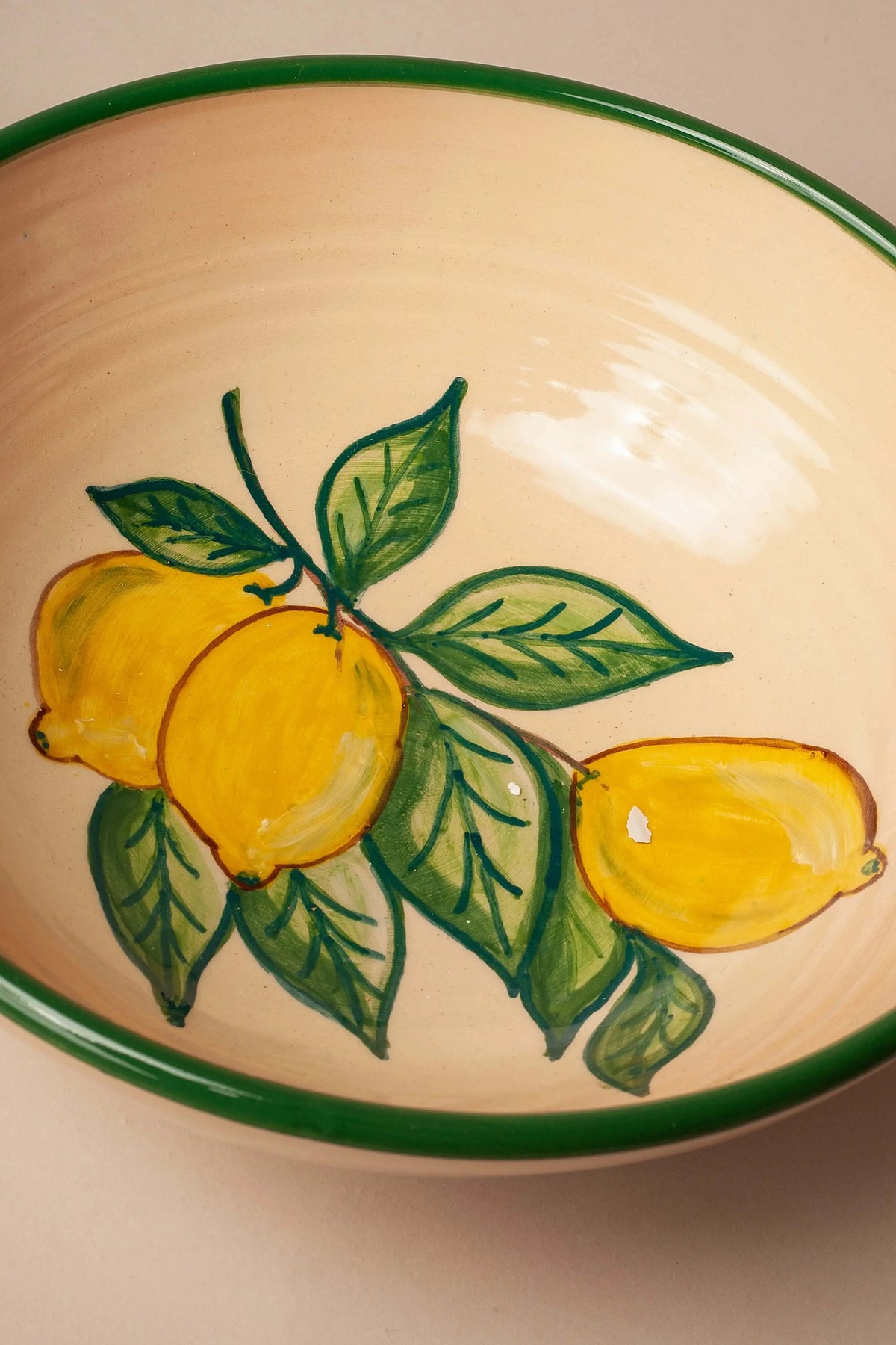 Ensaladera de cerámica color crema con estampado artesanal de limones amarillos y borde verde.