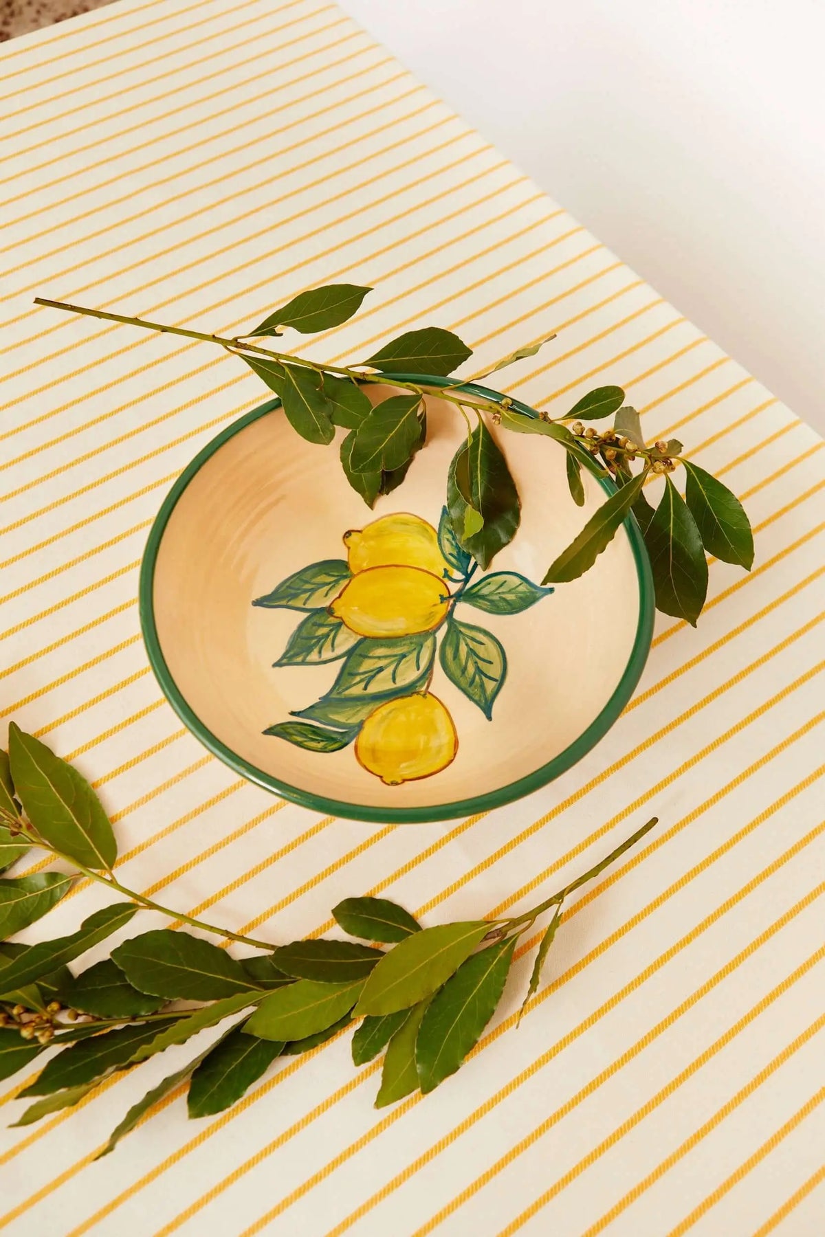 Ensaladera de cerámica con diseño artesanal de limones sobre fondo color crema y borde verde, decorada con laurel.