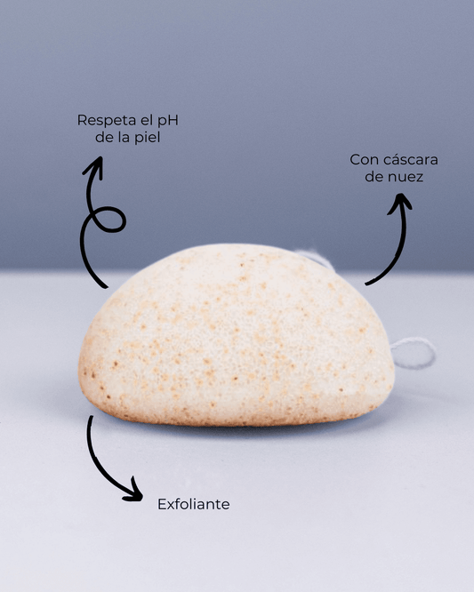 Esponja Konjac exfoliante Banbu de color crema con partículas de nuez sobre fondo gris, con etiquetas explicativas.