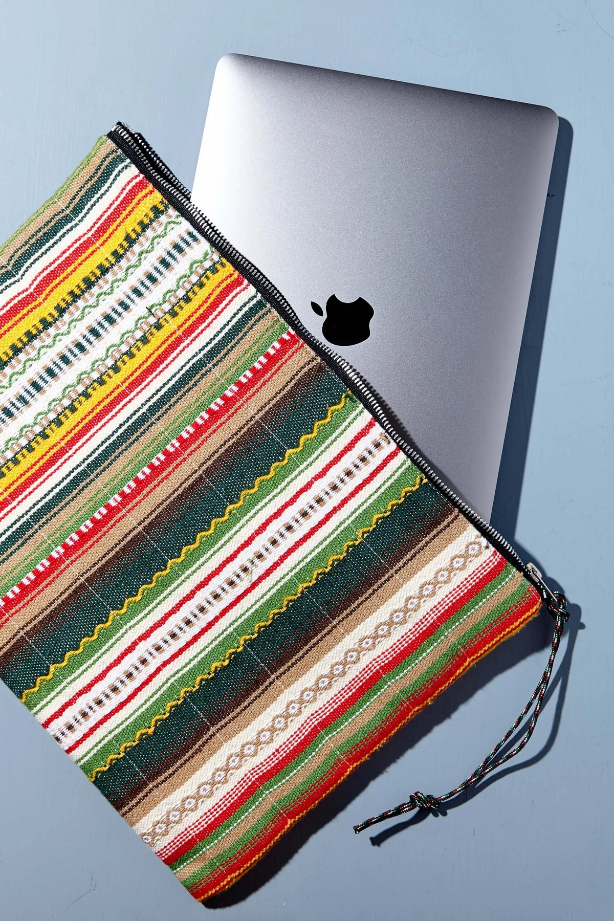 Funda de ordenador de tela artesanal con rayas multicolores, cierre de cremallera y estilo rústico étnico.
