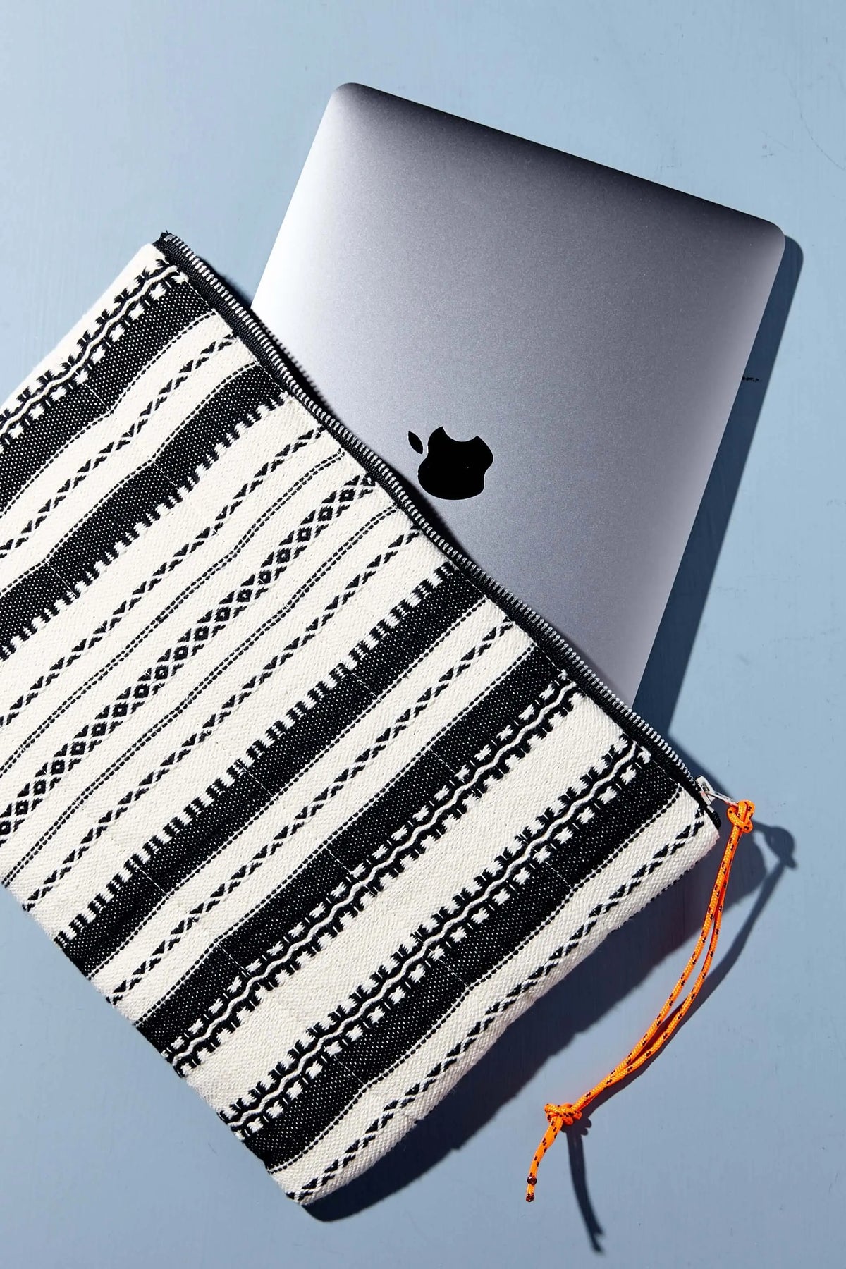 Funda textil de estilo alpujarreño en blanco y negro con patrón geométrico, cremallera negra y tirador naranja.