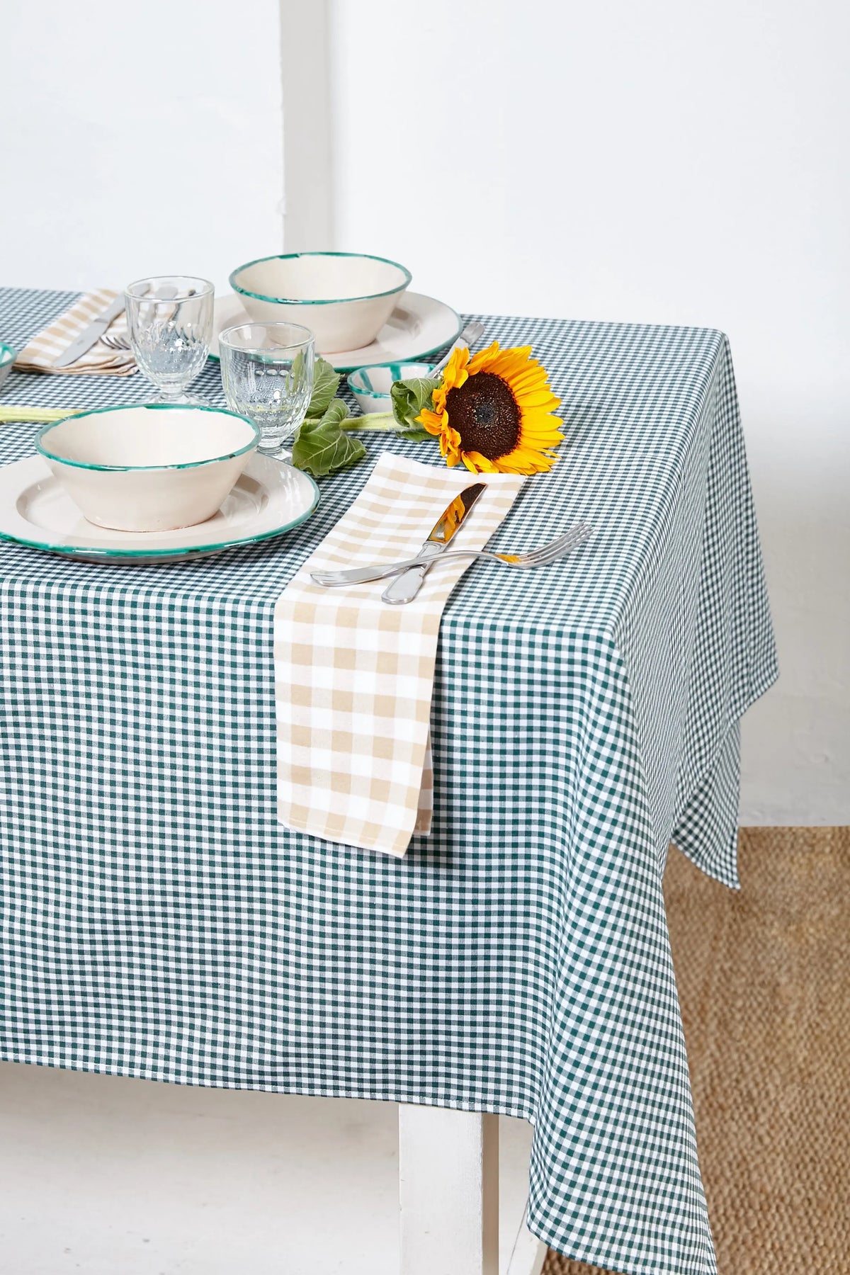 Bottle green and white gingham tablecloth, classic checkered fabric, styled with rustic tableware and a sunflower.