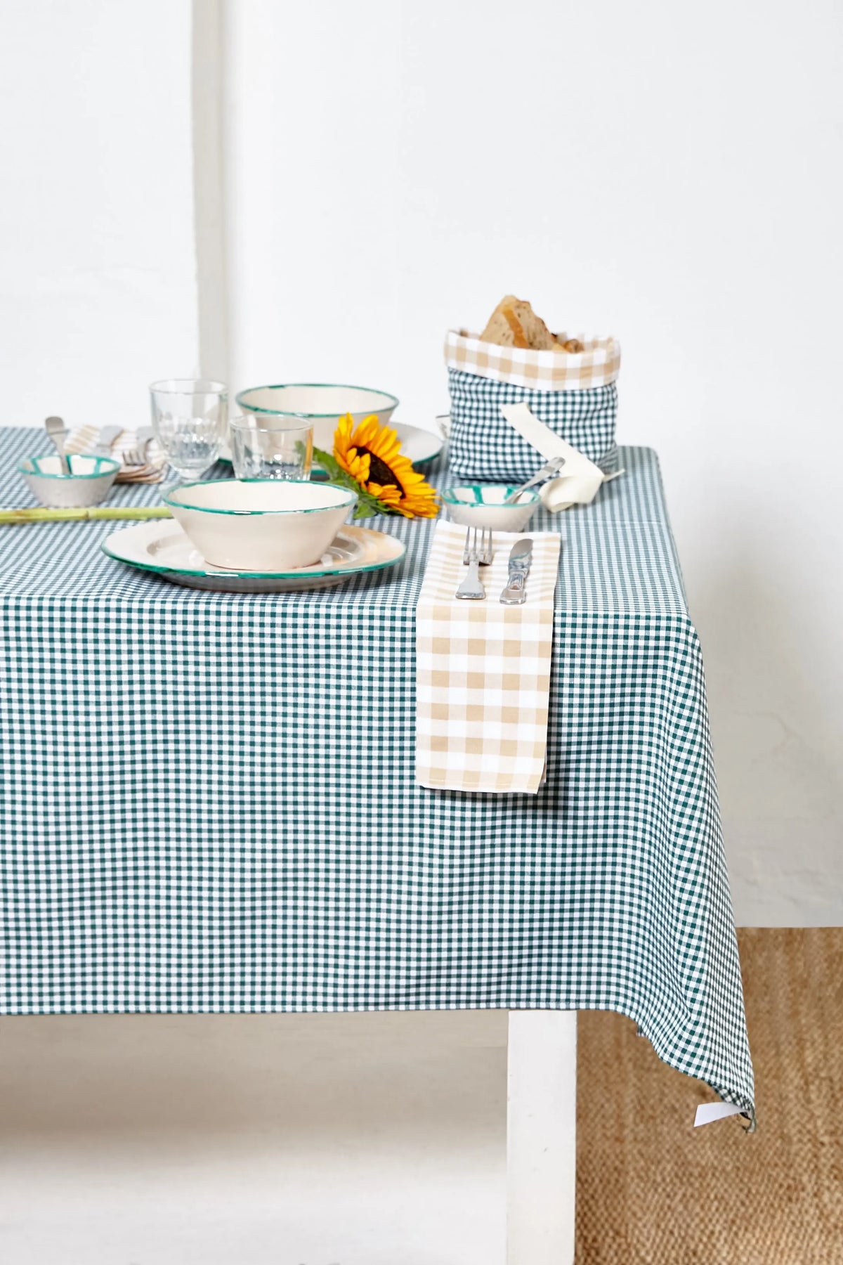 Mantel de tela con estampado de cuadros vichy en color verde botella sobre una mesa puesta.