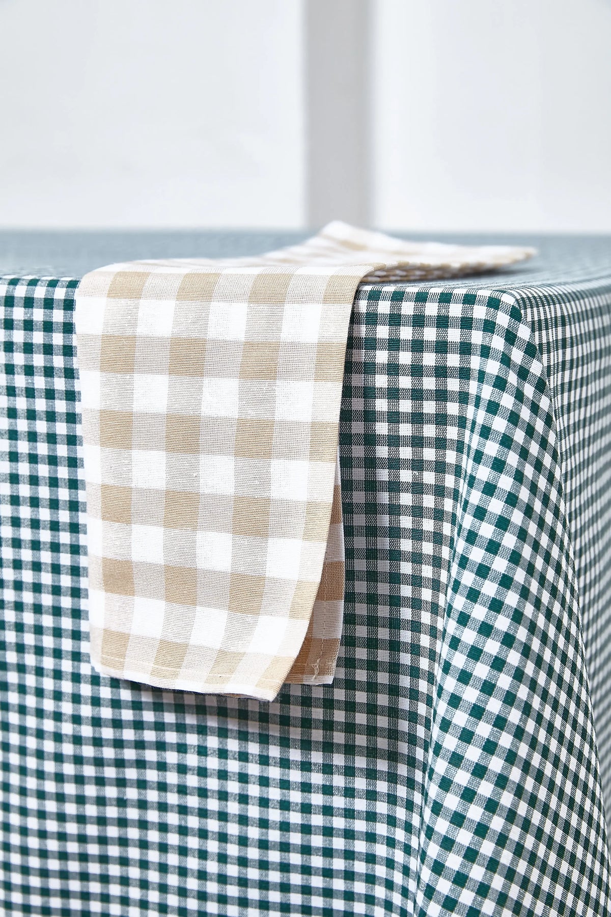 Bottle green and white gingham tablecloth with a beige and white checkered napkin draped on top.