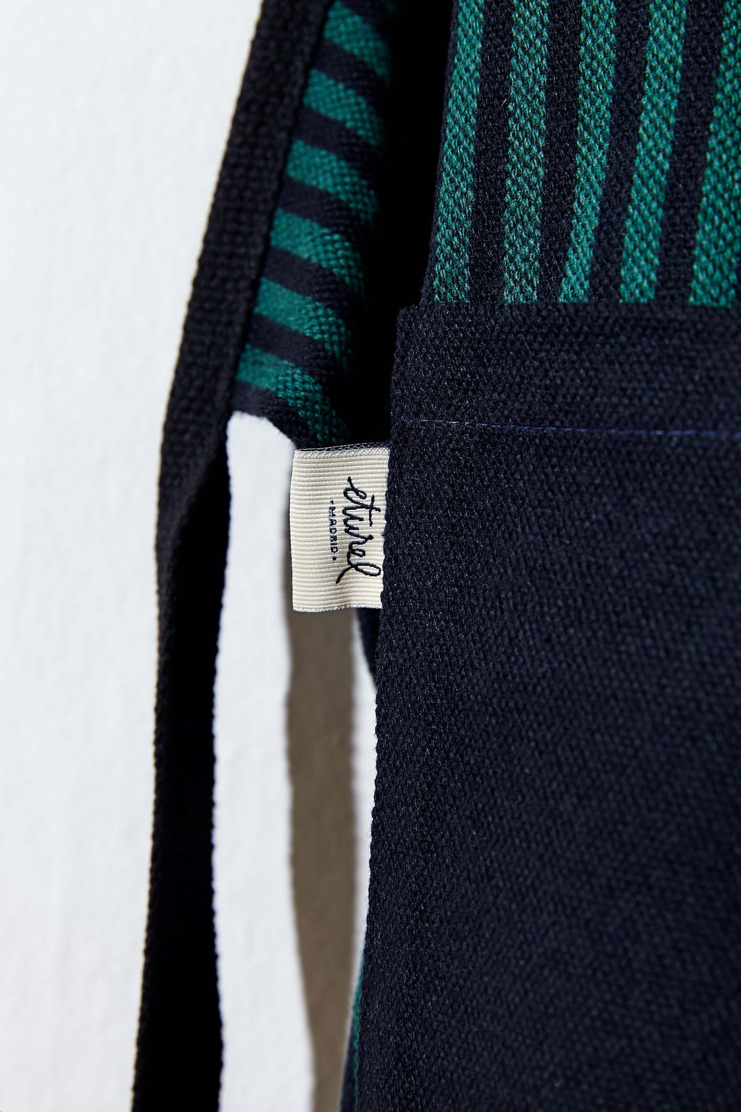 Detalle de etiqueta artesanal en delantal loneta estribera verde con rayas negras