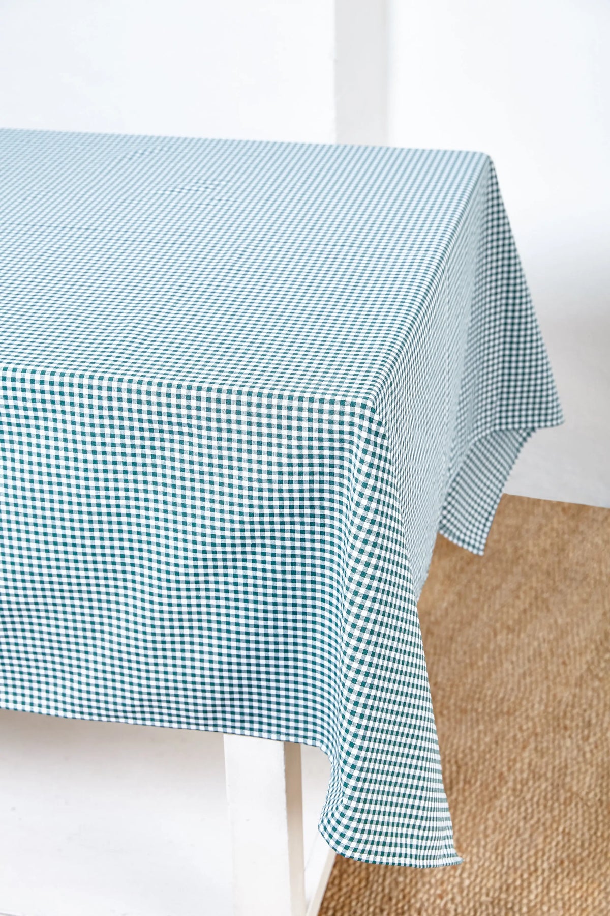 Mantel de tela con estampado de cuadros vichy en color verde botella sobre una mesa blanca.
