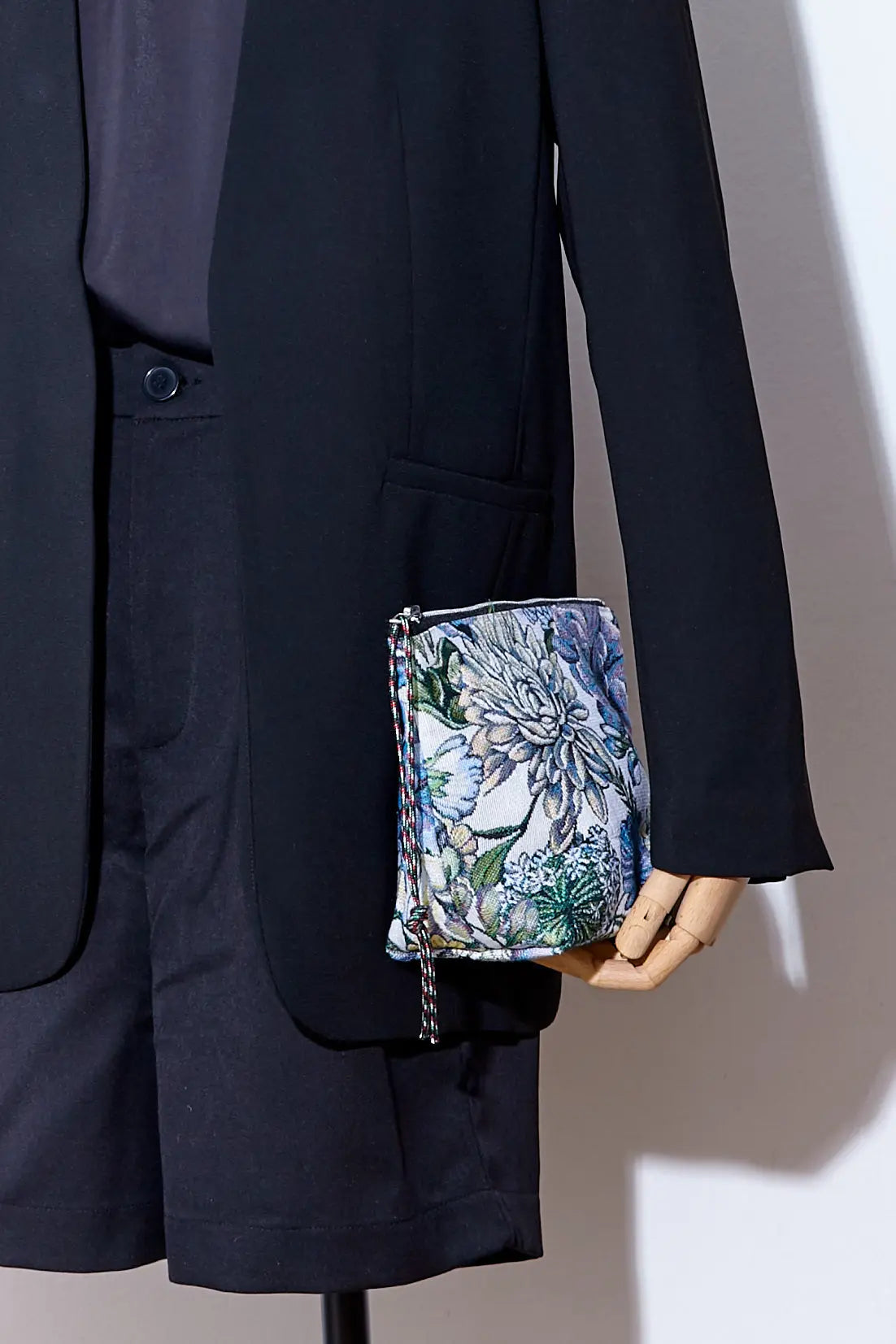 Small rectangular pouch in floral jacquard fabric with blue chrysanthemum pattern, held by a mannequin hand.