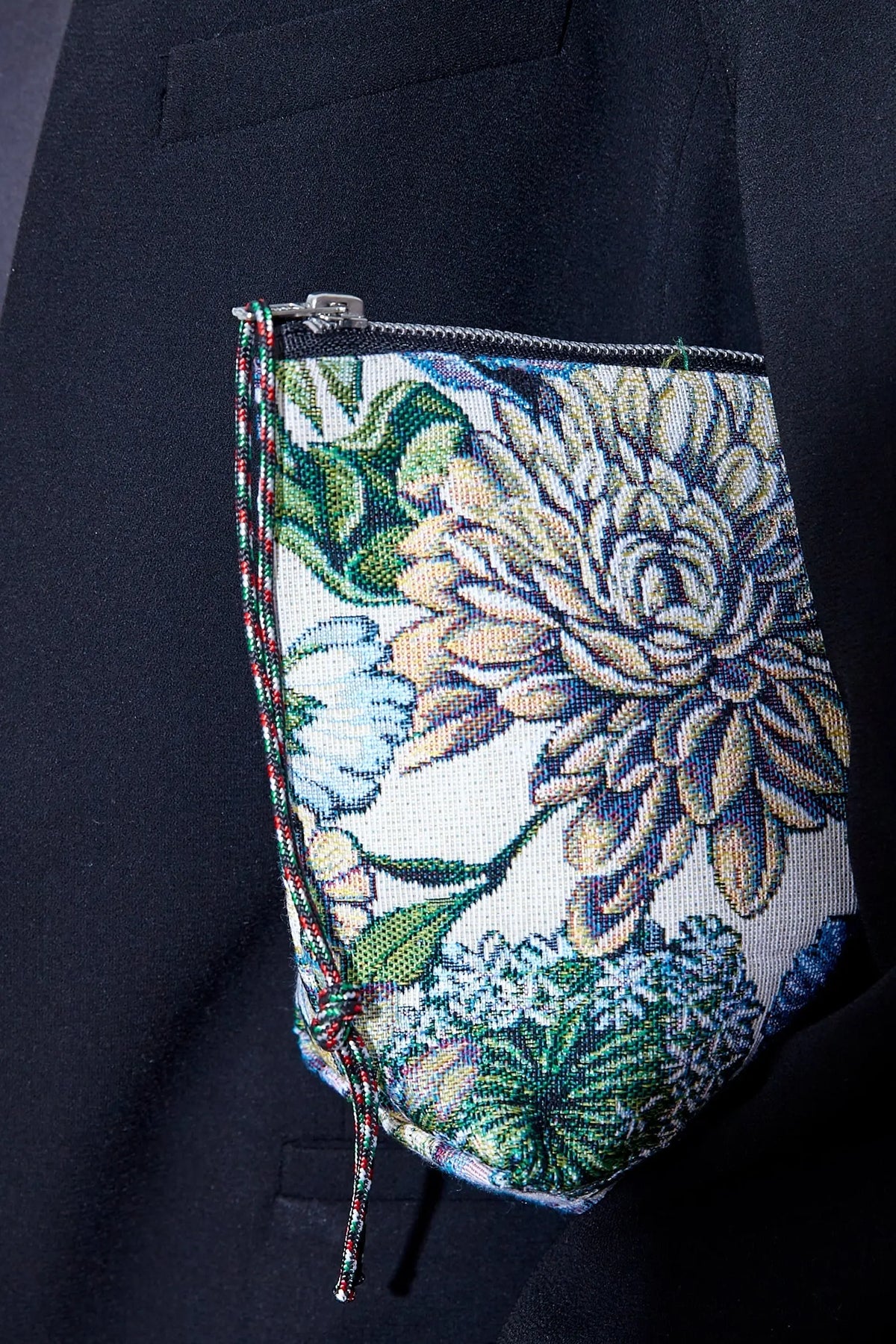 Neceser tipo estuche de tejido jacquard con estampado de crisantemos azules, cierre de cremallera y cordón decorativo.