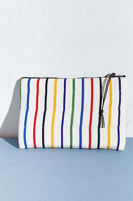 Funda rectangular de tela blanca con rayas verticales de colores, cierre de cremallera y cordón, sobre fondo azul.