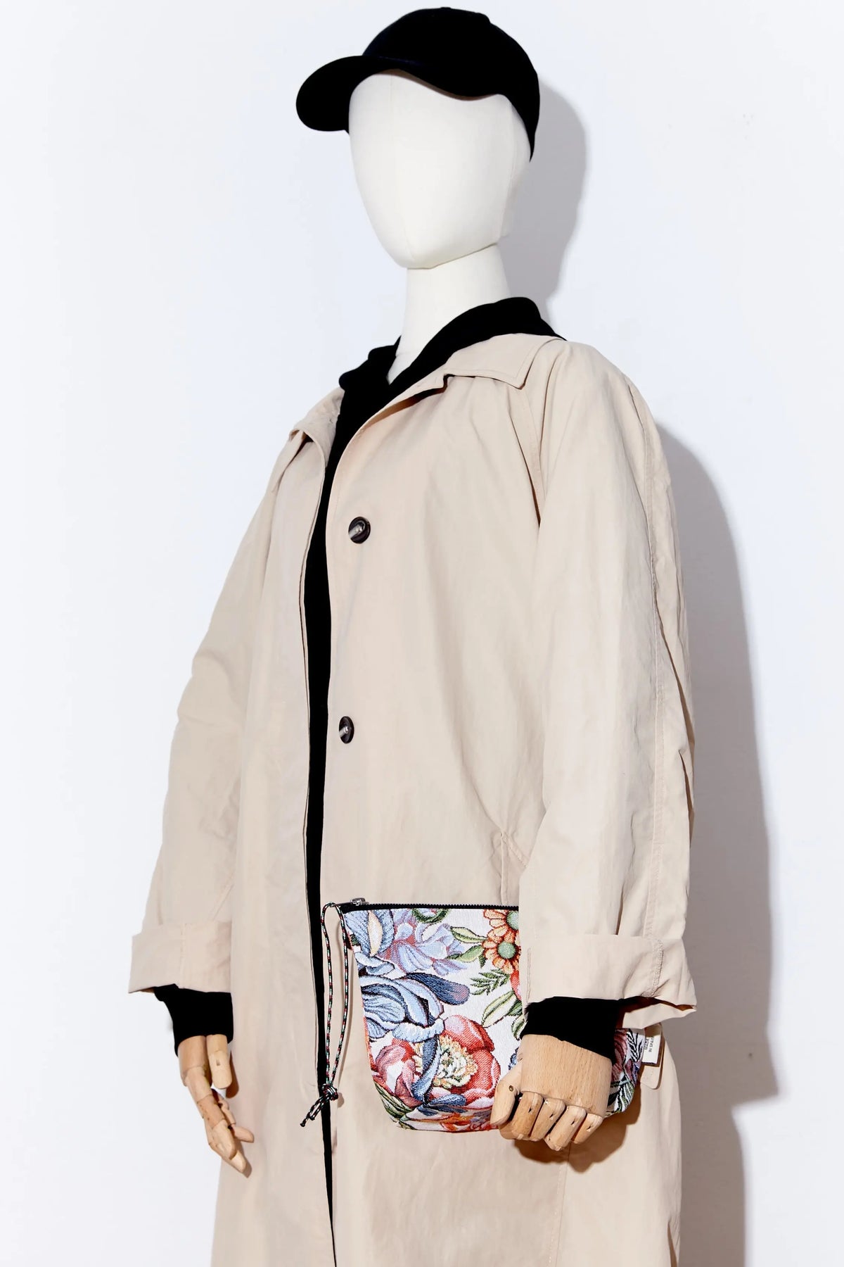 Neceser de tejido jacquard con estampado de crisantemos rojos y cierre de cremallera en mano de maniquí.