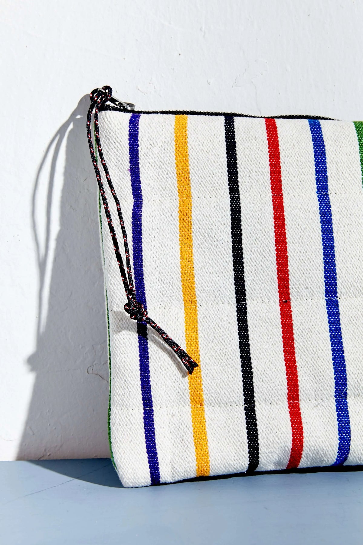 Funda para dispositivo de tejido blanco con rayas verticales de colores, cierre de cremallera con cordón y acabado acolchado.
