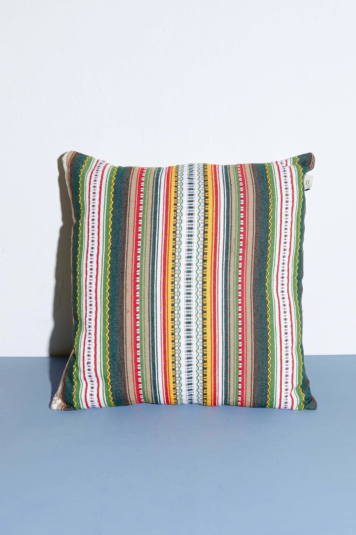 Cojín cuadrado de 50x50cm con diseño de rayas verticales multicolores en tejido tipo alpujarra de estilo artesanal.