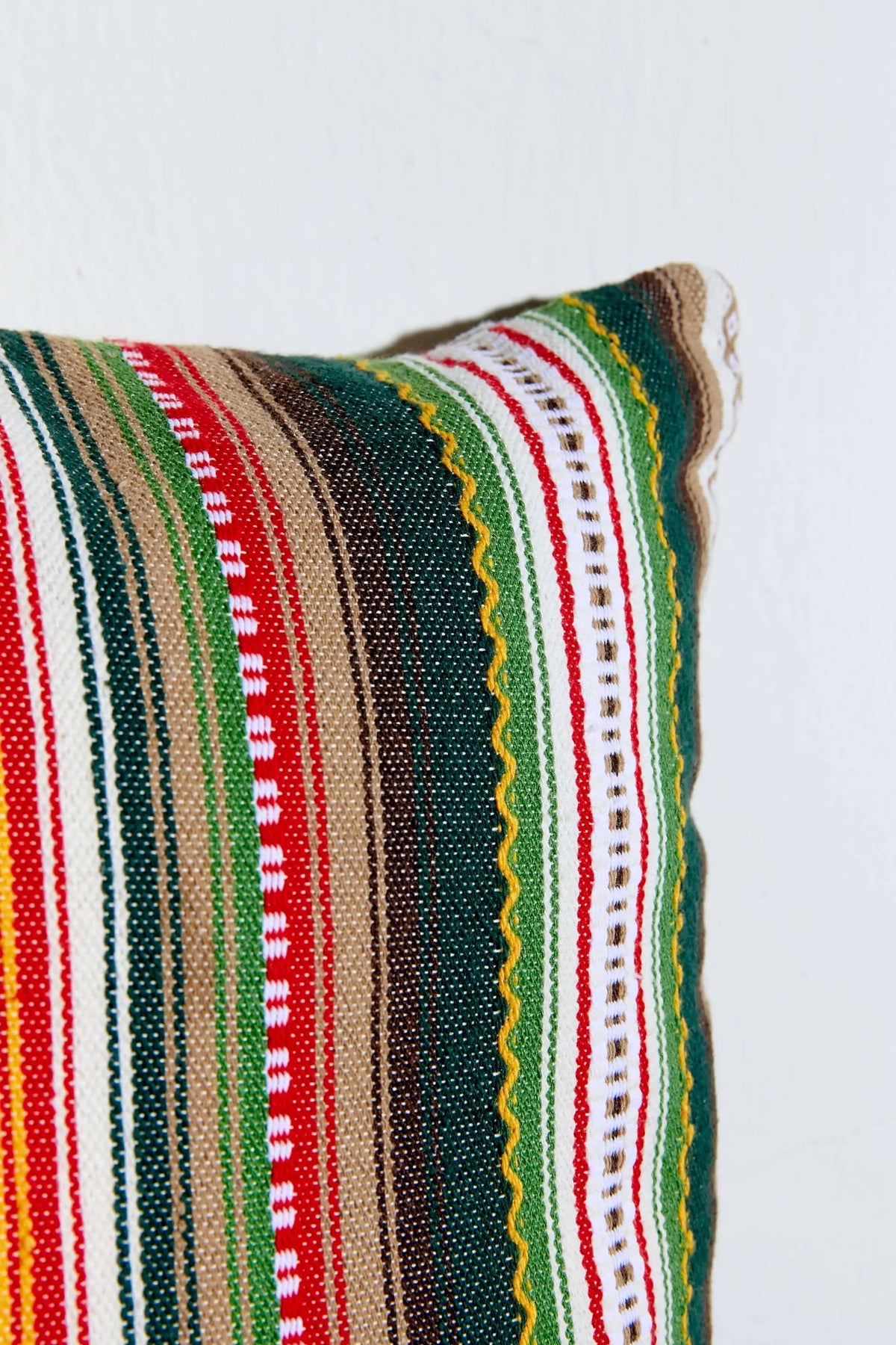 Funda de cojín con tejido alpujarreño de rayas verticales en verde, rojo, beige y blanco, con detalles en zig-zag.