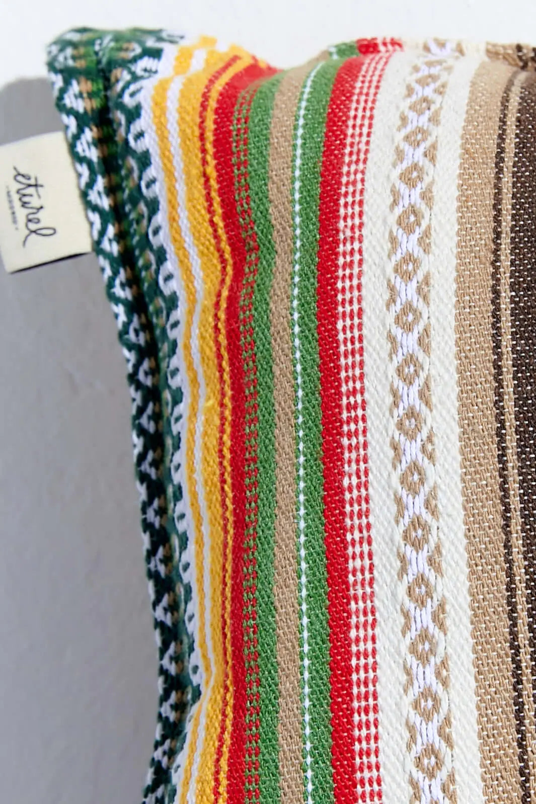 Funda de cojín rectangular con tejido de estilo alpujarreño, rayas multicolor en tonos tierra, verde, rojo y amarillo.