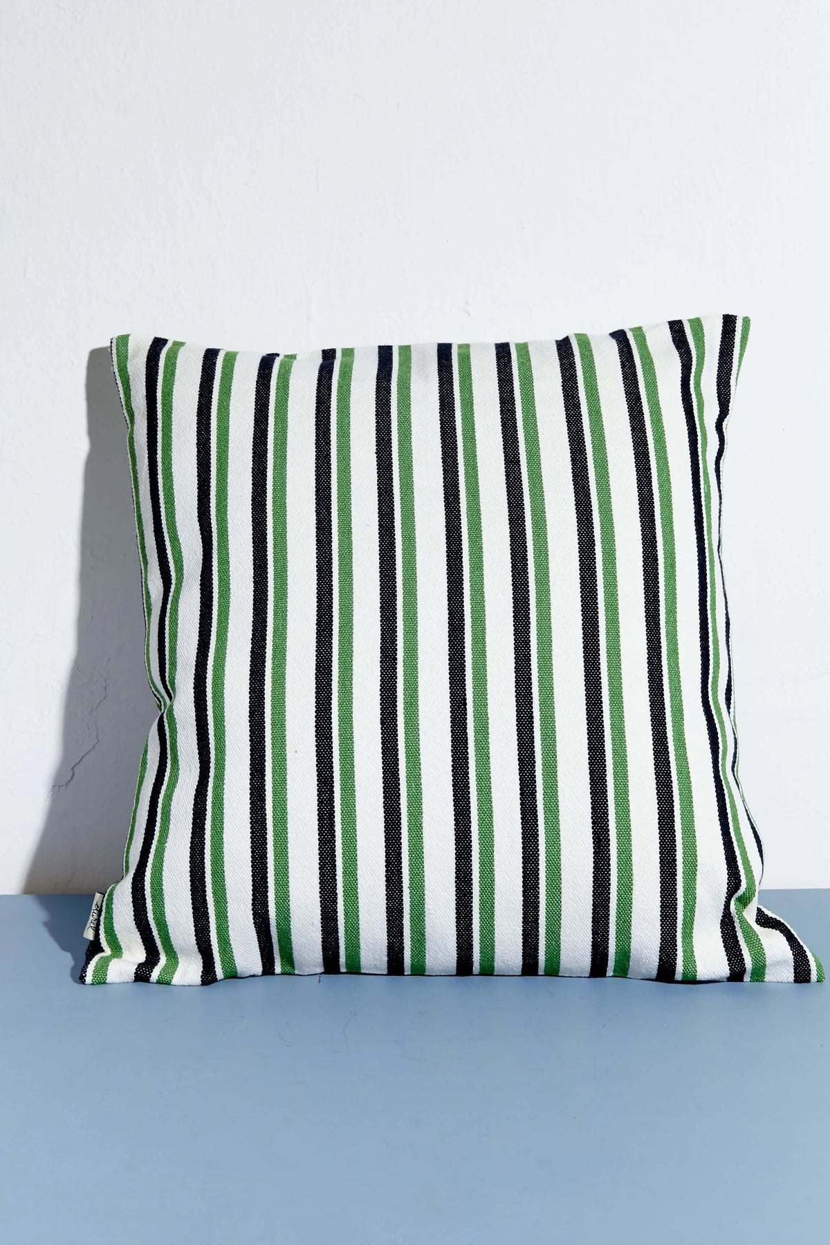 Cojín cuadrado (50x50 cm) de loneta con estampado de rayas verticales en verde, negro y blanco sobre fondo claro.