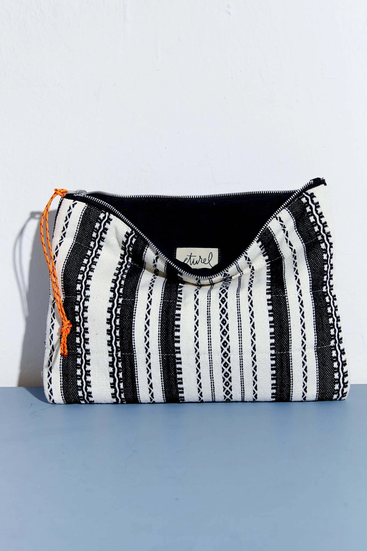 Funda para portátil y tablet con estampado de rayas alpujarreñas en blanco y negro, cierre de cremallera y tirador naranja.