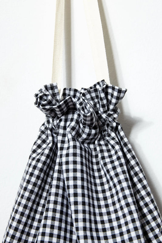 Black and white gingham fabric bread bag with a gathered drawstring top and off-white cotton ribbon handles.