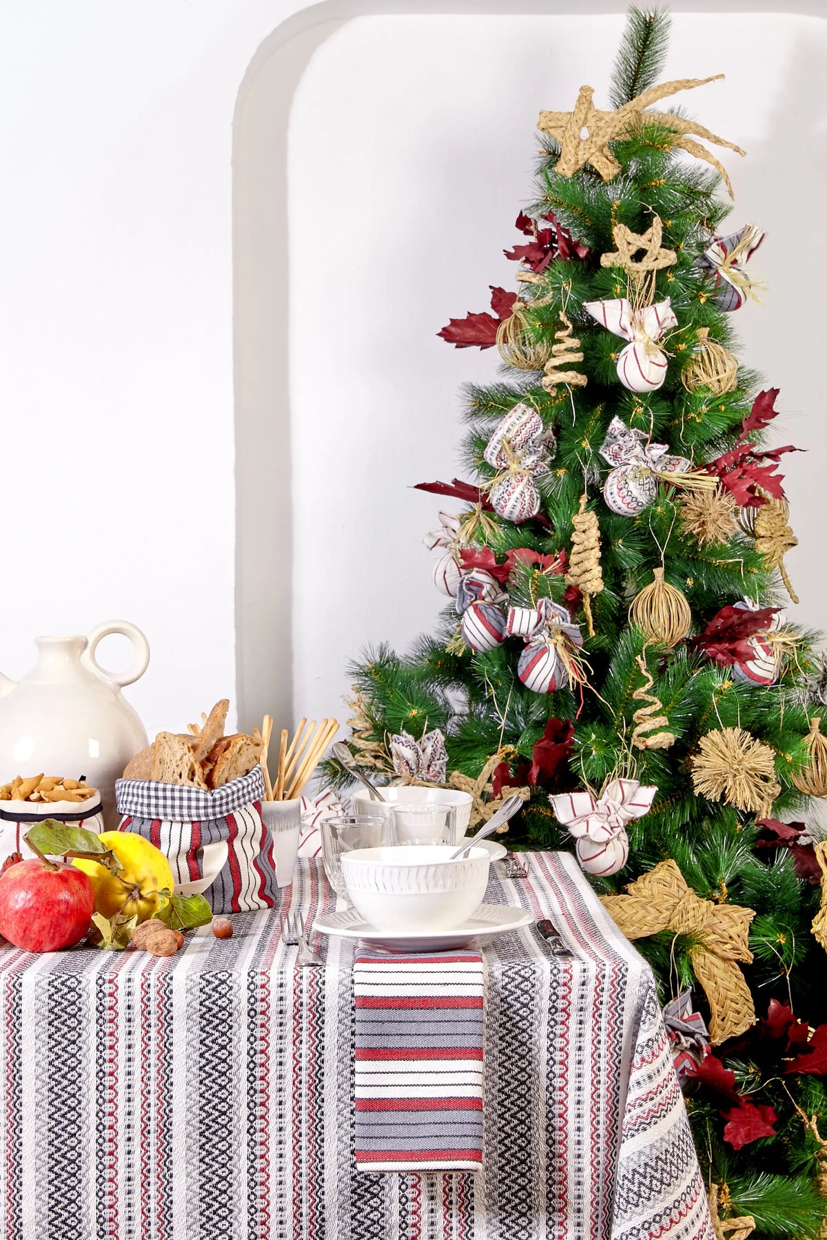 Maroon, grey, and white striped woven tablecloth with intricate geometric patterns set for a festive holiday meal.
