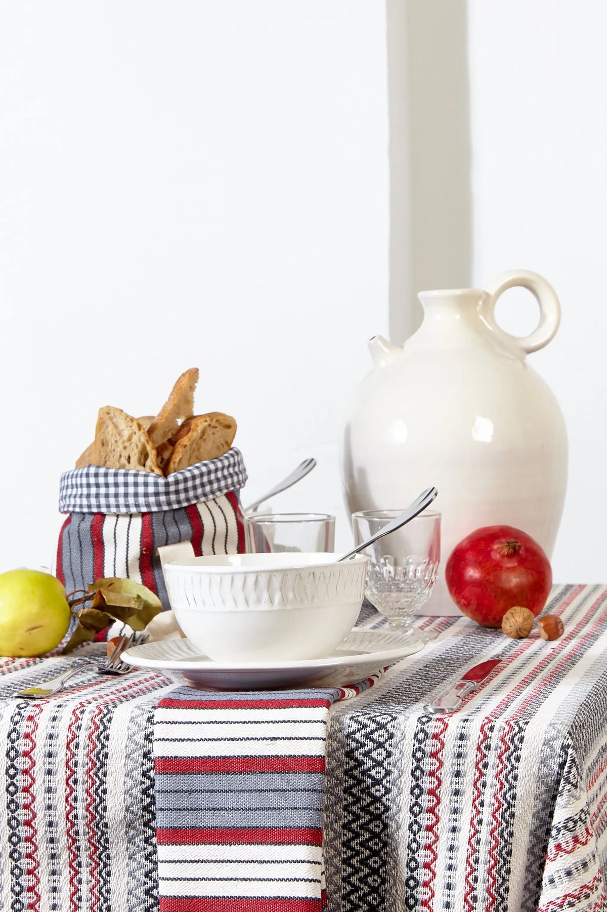 Mantel tejido estilo morellano con rayas verticales en tonos granate, gris y blanco sobre una mesa puesta.