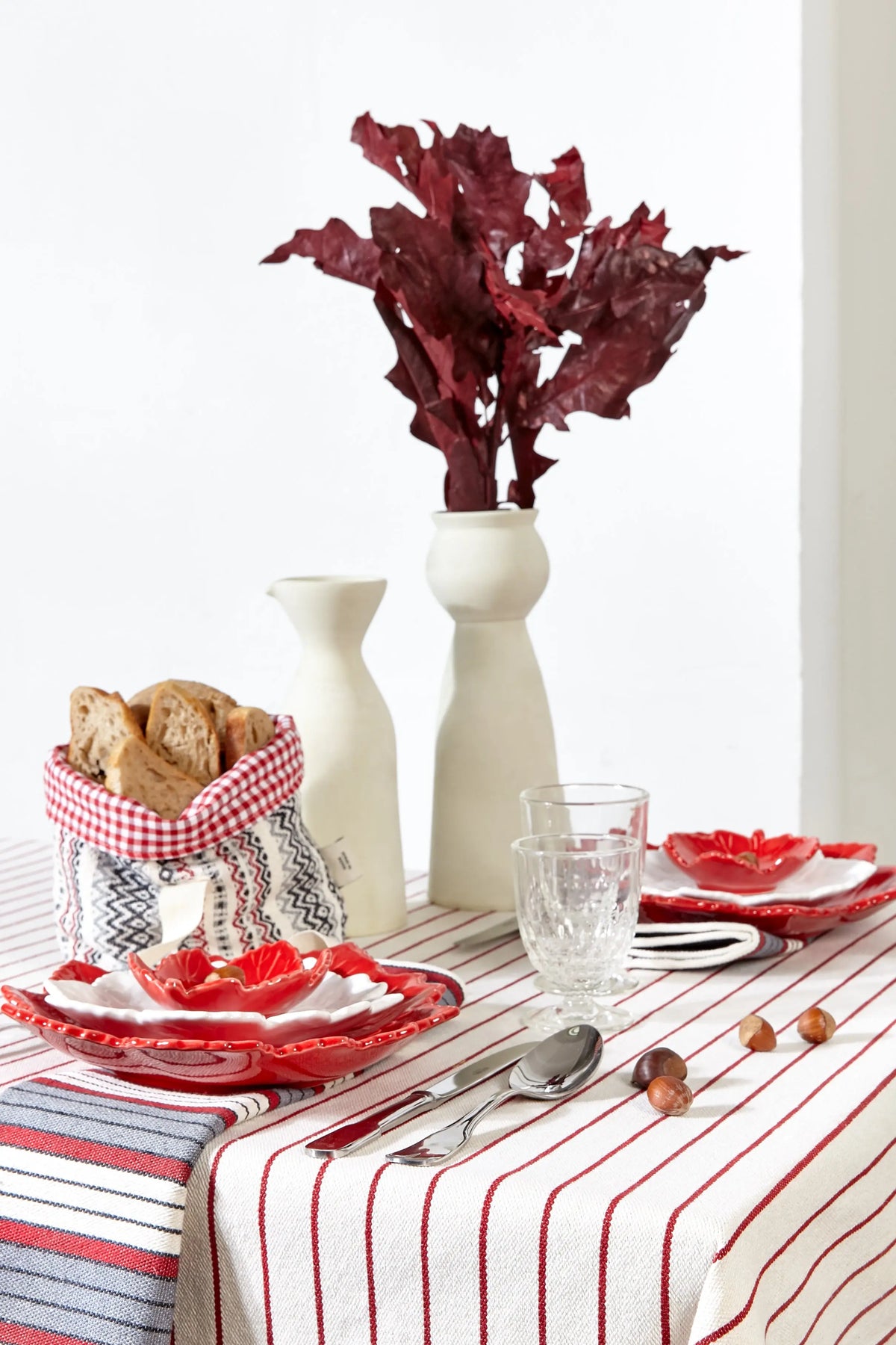 Mantel de loneta con diseño de rayas verticales granates, ideal para una mesa elegante con vajilla de estilo rústico.