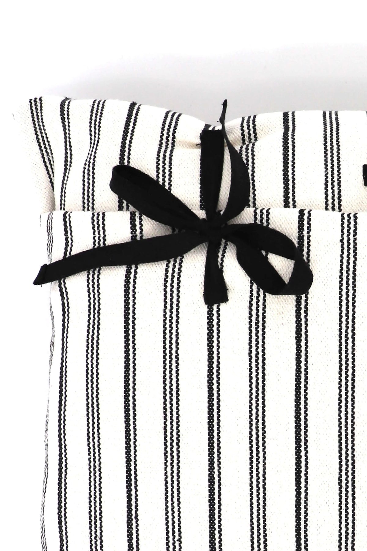 Funda de cojín de loneta blanca con rayas negras verticales, cerrada con un lazo de tela negra en la parte superior.