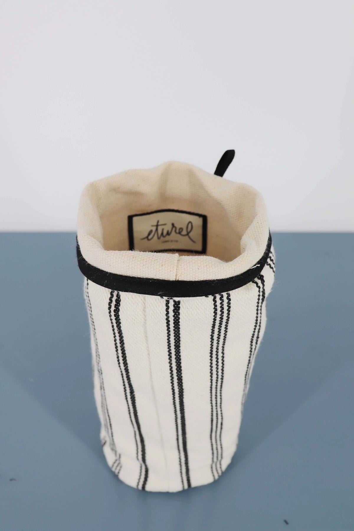 Funda para jarrón de loneta en color blanco con rayas verticales negras, estilo minimalista y acabado textil.