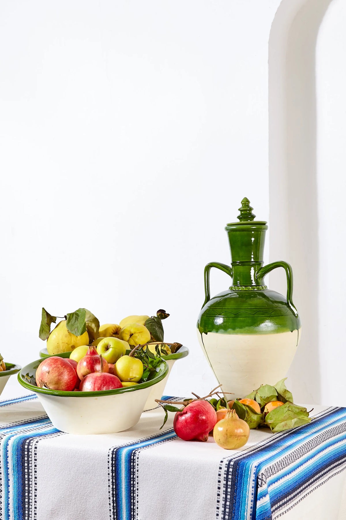 Blue-striped Alpujarra-style tablecloth featuring a woven fabric texture, displayed with a green jug and fruit bowls.
