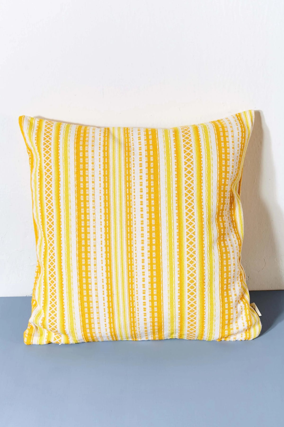 Funda de cojín cuadrada 50x50cm con diseño de rayas y patrones geométricos en tejido alpujarra de color amarillo.