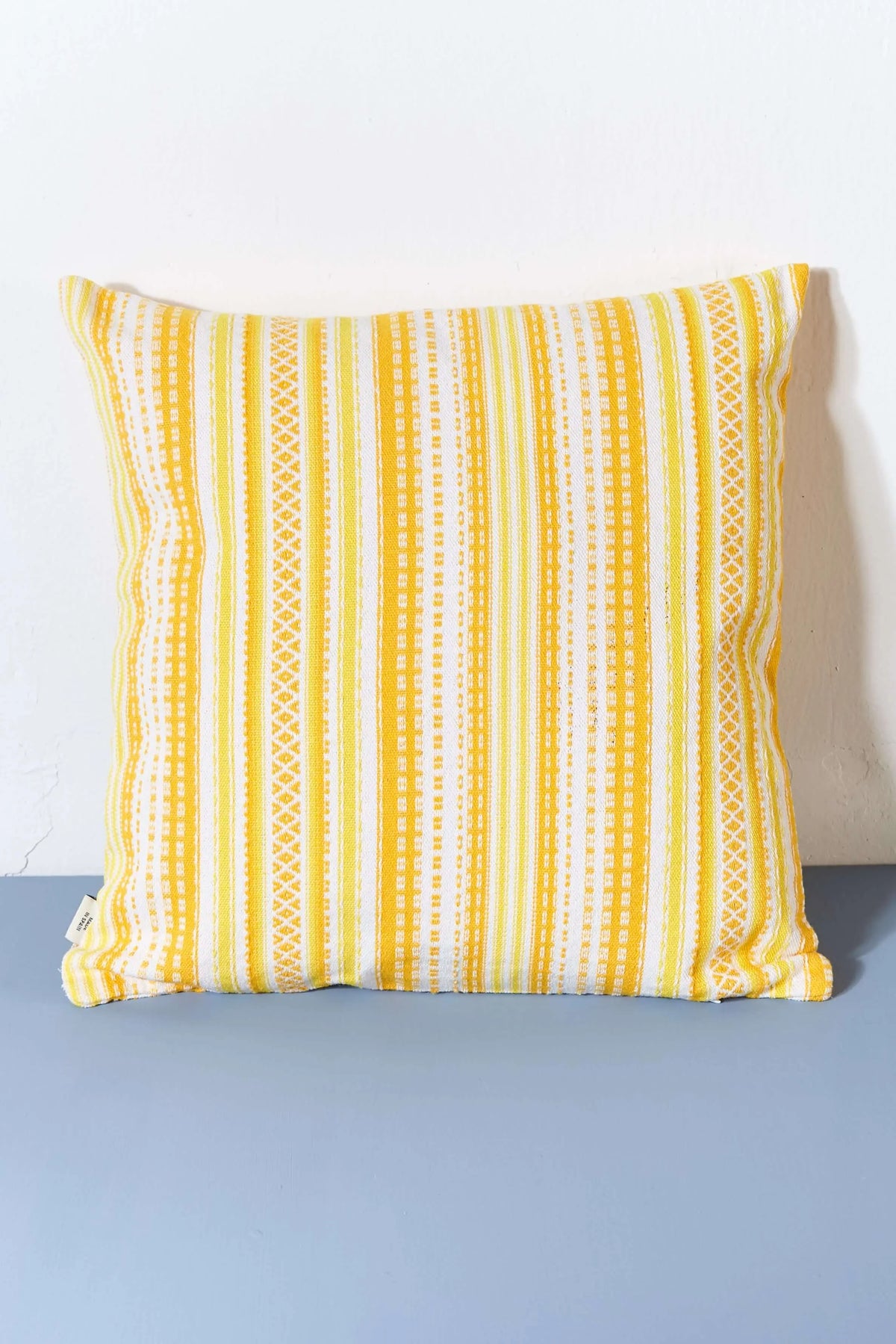 Funda de cojín 50x50 cm con tejido artesanal estilo alpujarra en tonos amarillo y blanco con patrón de rayas.