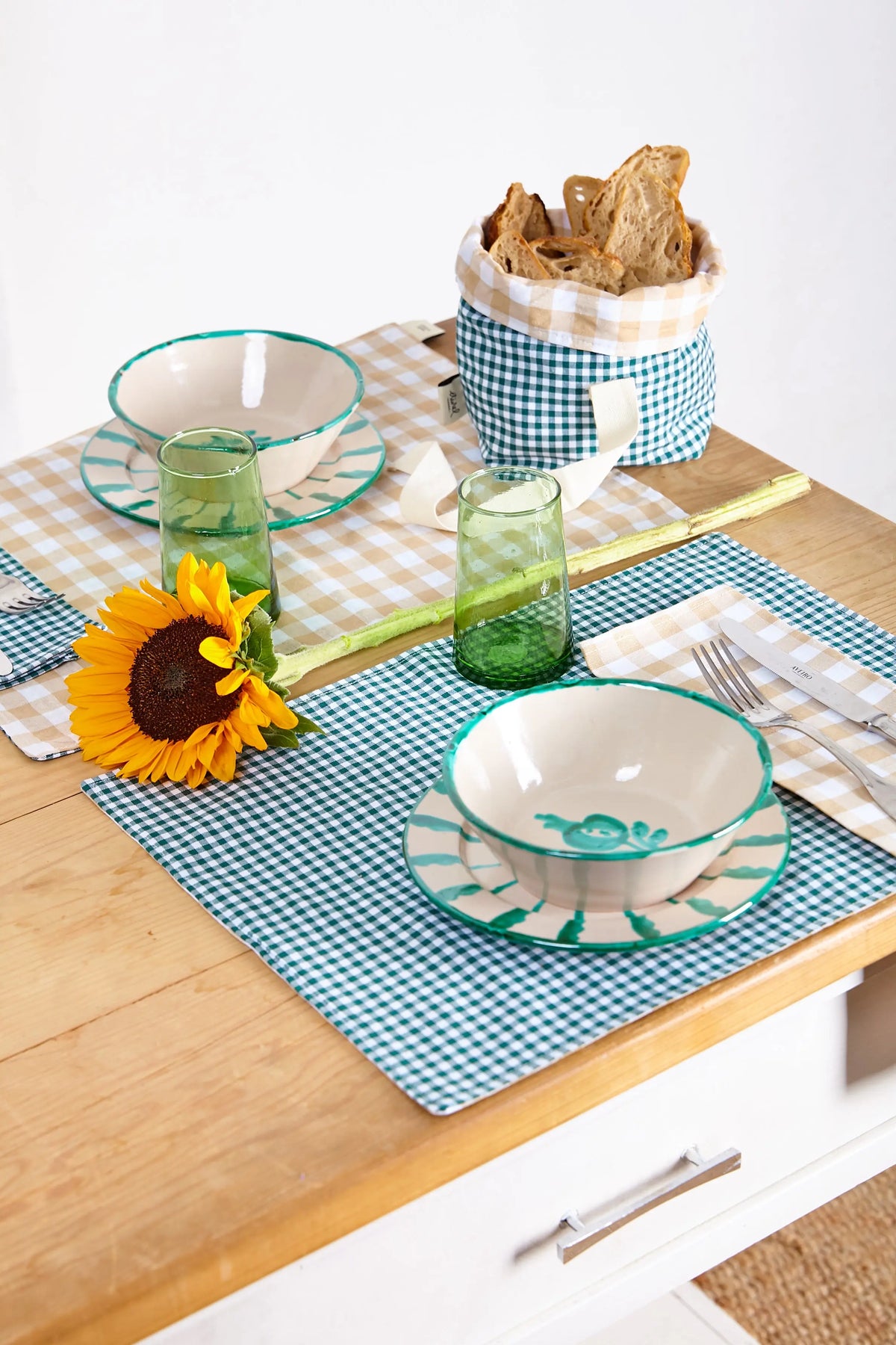 Pack de dos servilletas de tela con estampado vichy verde y blanco sobre una mesa de madera con vajilla decorada.
