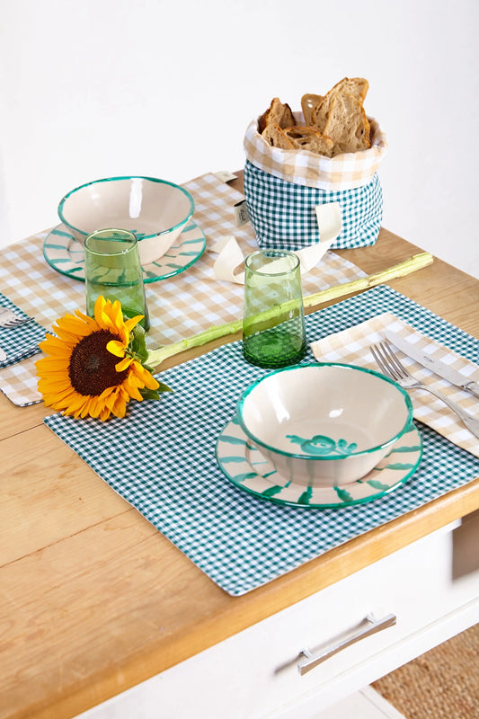 Pack de dos servilletas de tela con estampado vichy verde y blanco sobre una mesa de madera con vajilla decorada.