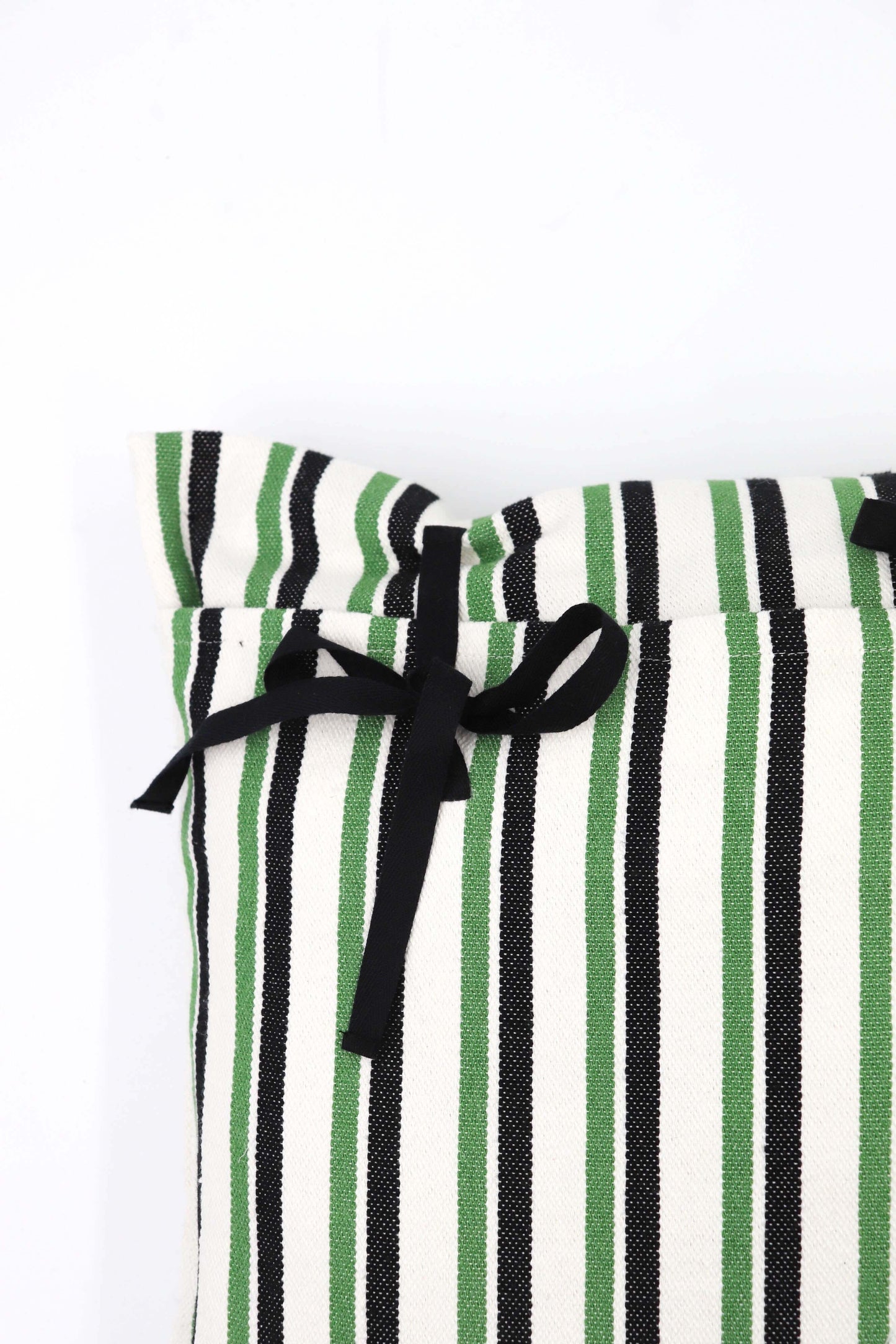 Funda de cojín de loneta a rayas verticales verdes, negras y crudas, con cierre de lazos negros en la parte superior.